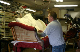 man replacing fabric on a vintage couch