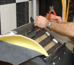 man repairing fabric on a leather chair
